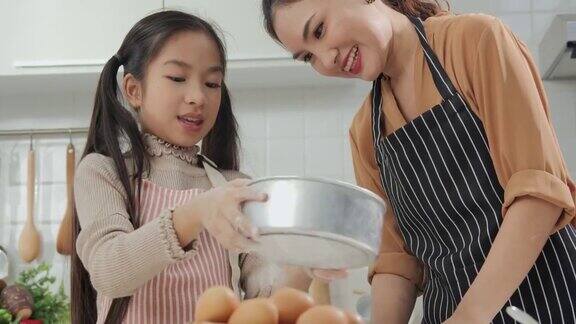 年轻的母亲和小女孩在厨房准备食物妈妈教小女孩做饭