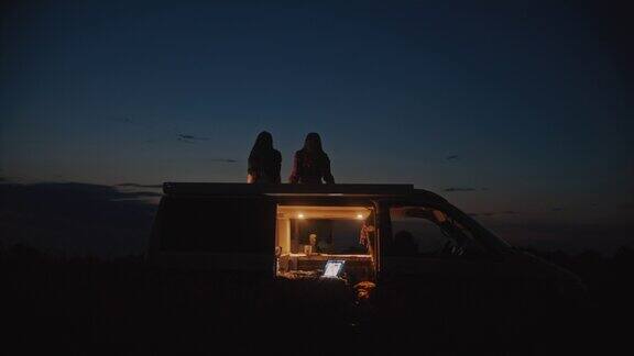 DS晚上两个女人在野外露营的屋顶上休息