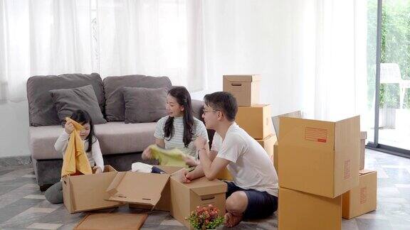 快乐的亚洲家庭搬到新房子用纸箱和整理房子