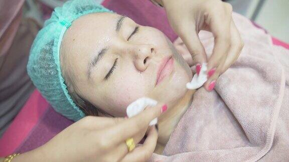 一名护士正在擦拭一名亚洲妇女的脸在美容诊所医疗和美容皮肤科预约概念