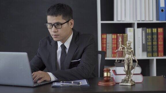 亚洲男性律师工作与锤子笔记本电脑正义女神在律师事务所在线咨询