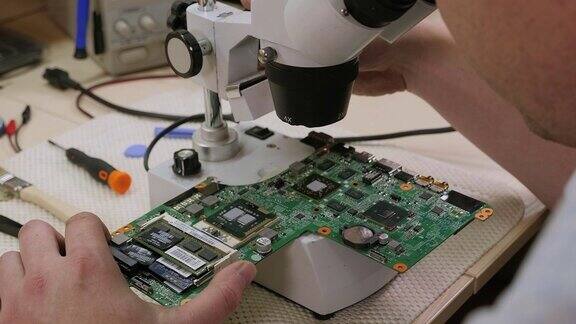 维修工在服务中心用显微镜修理电脑