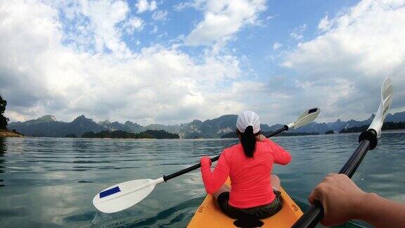 亚洲妇女皮划艇在早晨与阳光热带大湖放松的运动