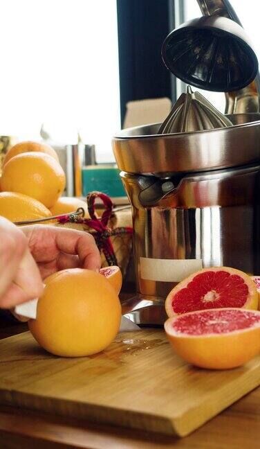 垂直的画面男性的手正在榨汁机前切柚子健康食品和素食主义