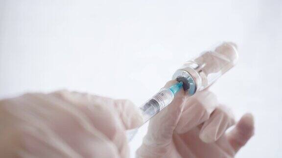 特写医生的手在手套填充注射器与疫苗从瓶