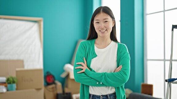年轻的中国女子微笑着自信地站在新家双臂交叉