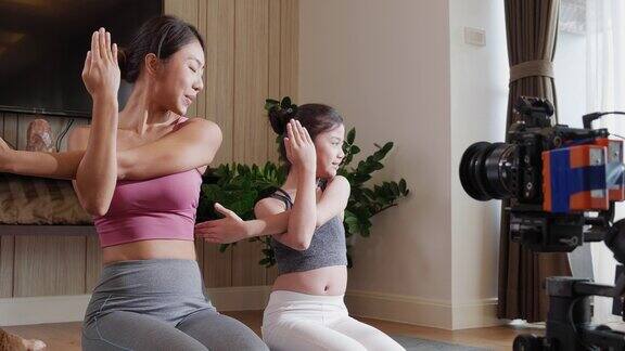 专业的亚洲瑜伽教练和女儿在社交媒体上创建健康生活和健身在线课程