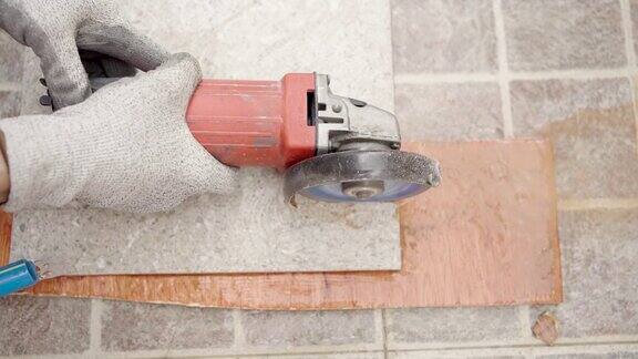 近距离使用圆锯机刀片切割瓷砖地板的人的手并使用水来防止切割引起的灰尘分散