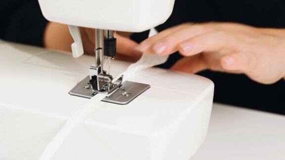 一名女裁缝在缝纫机上缝制白色织物