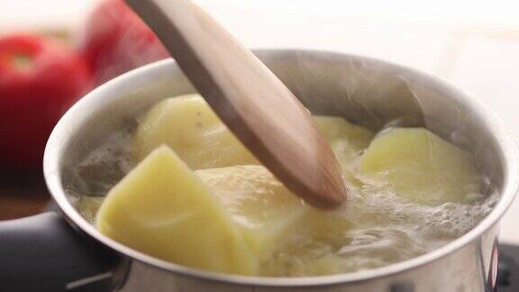 将土豆放入盛有沸水的炖锅中用锅铲搅拌