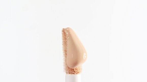 化妆液米色粉底浇在化妆刷上特写化妆品滴bb霜在白色背景微距镜头漂亮的化妆品