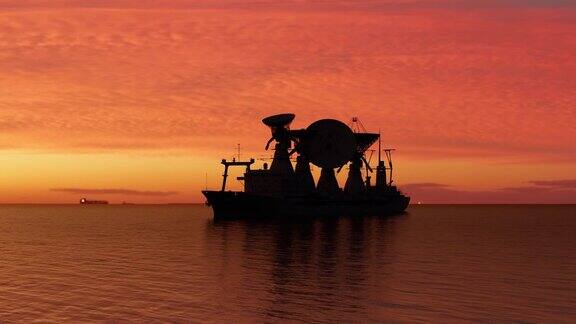 海上一艘船上的卫星天线日落后科学船的轮廓映衬着天空
