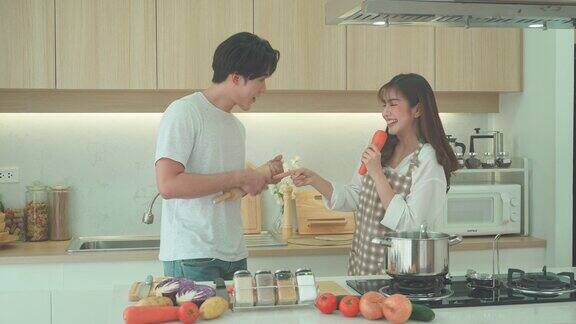 亚洲夫妇在家里的厨房里一边做饭一边唱歌一对情侣的浪漫场景