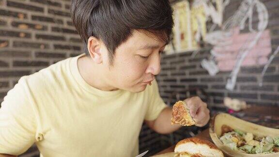 与朋友共进午餐时一个年轻人正在切奶酪汉堡和洋葱圈