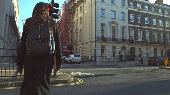 一个穿着大衣背着背包的女游客在闯红灯时过马路