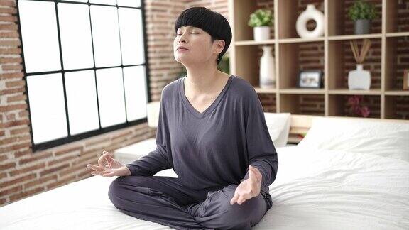 年轻的中国女子坐在卧室的床上做瑜伽练习