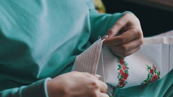 美丽的女性双手在家里用线和针手工缝制