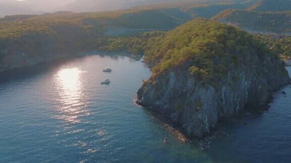 俯瞰海湾、岩石海岸、绿树和游艇海景清澈平静的海水无人机拍摄的航拍画面