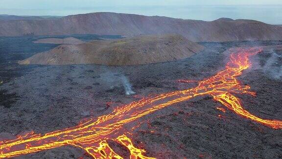 冰岛火山喷发大自然的奇迹炽热的熔岩从地面喷发出来无人机在活跃的火山口上空飞行熔岩穿过深色岩石表面凝固开裂