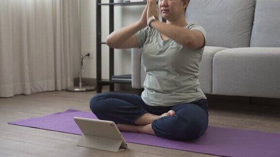 一个亚洲女人坐在家里的垫子上做瑜伽