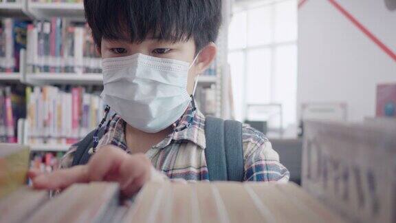 戴面具的亚洲男孩走进图书馆找书