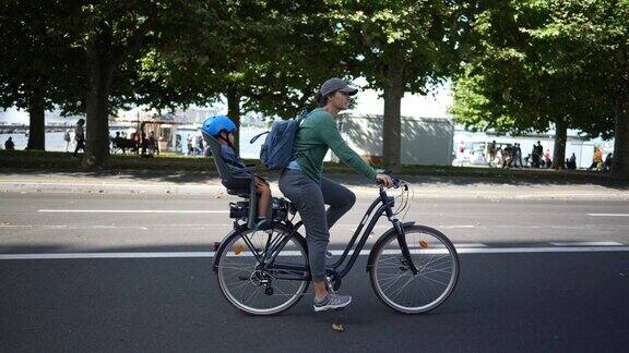 父母骑着自行车在街上孩子睡在后座上母亲骑着自行车