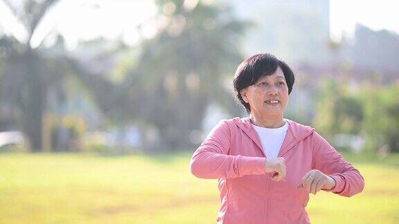 一位亚洲华裔老年妇女早上在公园做热身运动
