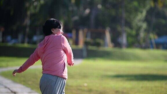 一位亚洲华裔老年妇女早上在公园做热身运动