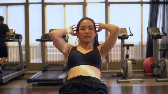 亚洲女运动员在健身房做仰卧起坐