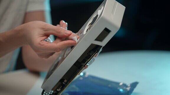 在家中维修和服务期间无法辨认的男性PC用户用小湿抹布清洁现代游戏显卡的冷却器刀片的特写