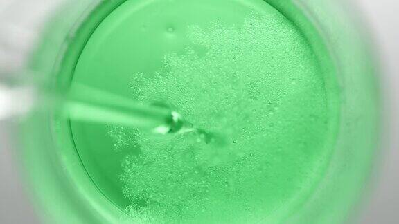 滴管将油注入烧杯中的绿色液体中产生气泡