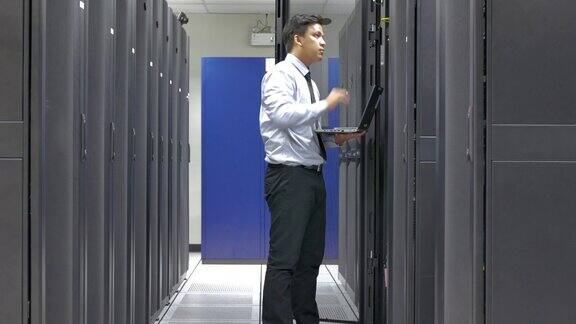 系统管理员使用笔记本电脑检查数据中心的服务器和设备