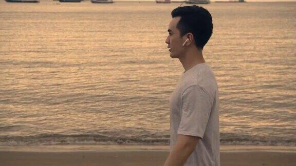 迷人的亚洲男子在海滩上散步在美丽的日落在夏天户外运动训练概念