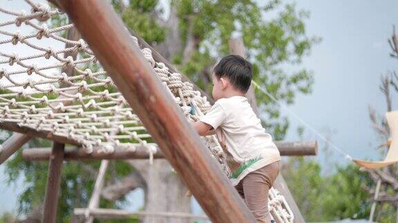 小男孩爬上绳梯攀爬方格架