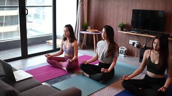 一群亚裔中国女性朋友在家庭客厅里一起练瑜伽