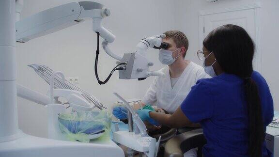 男牙医透过牙科显微镜检查病人的牙根管