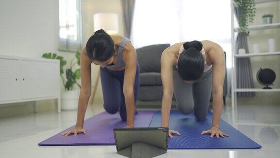 两个女人在电子平板前练习瑜伽