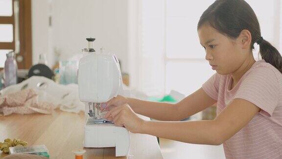 亚洲混血的青春期前女孩在家里学习如何缝制发卷