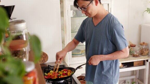 (中景)一个年轻人正在家里做饭