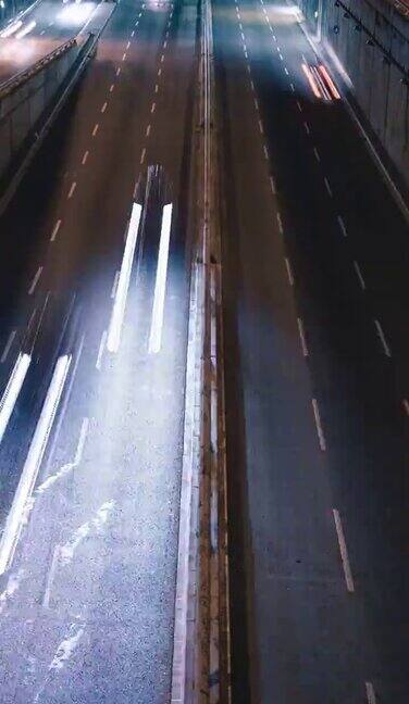城市高速公路的夜晚时光流逝快速交通移动的汽车行驶画着光的轨迹(垂直视频)