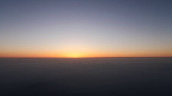 从山顶看日出的4K延时镜头太阳从云层地平线升起金色的太阳与温暖的云和蓝天背景