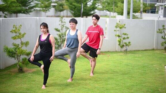 亚洲华人中年妇女练习瑜伽的房子前院上午与朋友