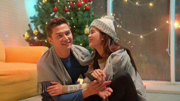 年轻的亚洲夫妇在庆祝冬季节日期间在家里看电视电影