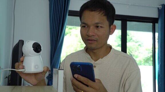 亚洲男性在家里使用智能手机连接闭路电视安全系统
