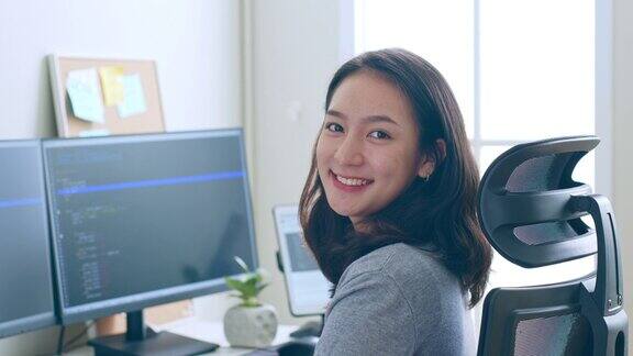 肖像年轻的亚洲女性开发人员程序员软件工程师IT支持看着相机和微笑享受在办公室工作