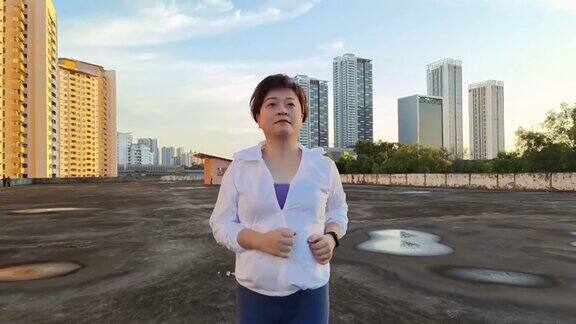 亚洲华人中年女性穿着运动服在屋顶停车场跑步