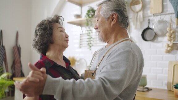 亚洲成熟的老年夫妇在家里的厨房里跳舞和微笑