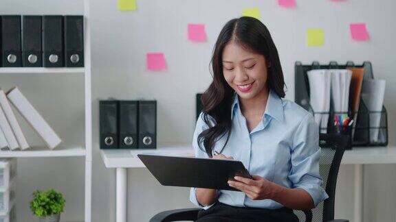 年轻聪明的亚洲女商人一边在办公室工作一边分析文件