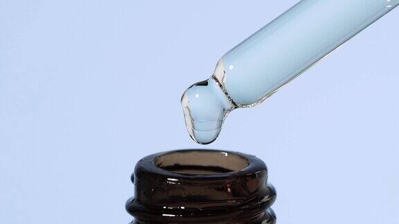 一滴精油精华液从玻璃滴管滴进棕色瓶子里美容背景水疗程序