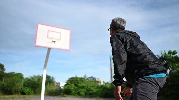 早上一名亚裔中国男子在篮球场练习篮球比赛